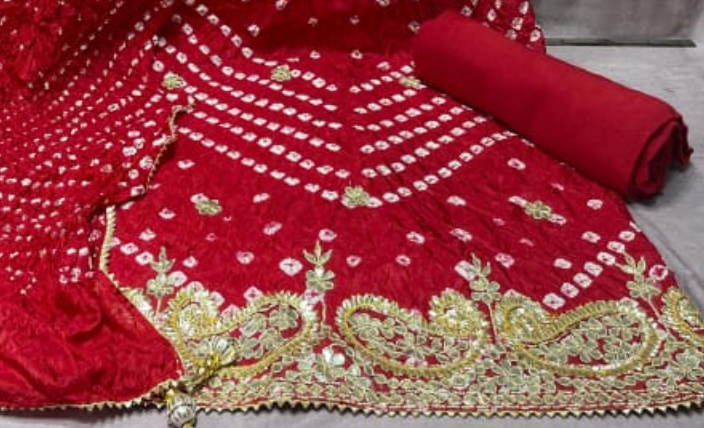 Red embroidered fabric with gold detailing on a plain background