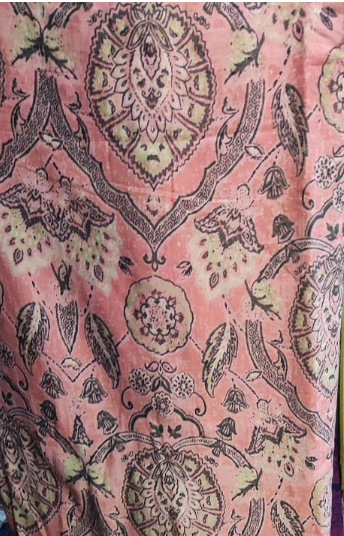 Patterned fabric with intricate designs on a pink background