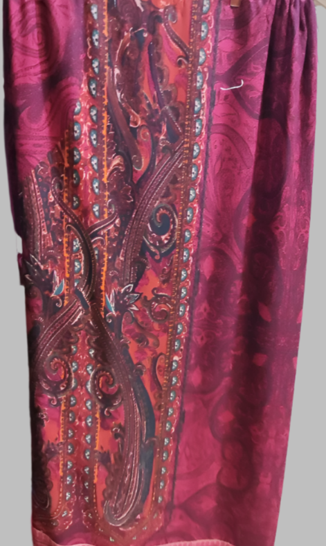 Red patterned fabric hanging on a rack with other colorful fabrics in the background