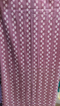 Purple fabric with white patterns on a hanger against a colorful background