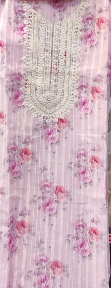 Floral dress with pink accents hanging against a tiled wall.