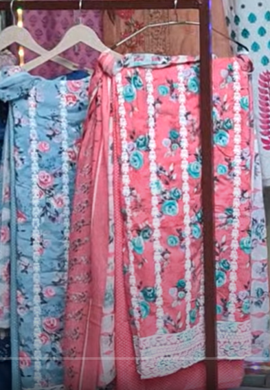 Floral-patterned dresses hanging on a rack with a pink dress in the foreground.