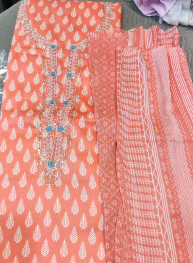 Coral fabric with white patterns and embellishments on a gray surface